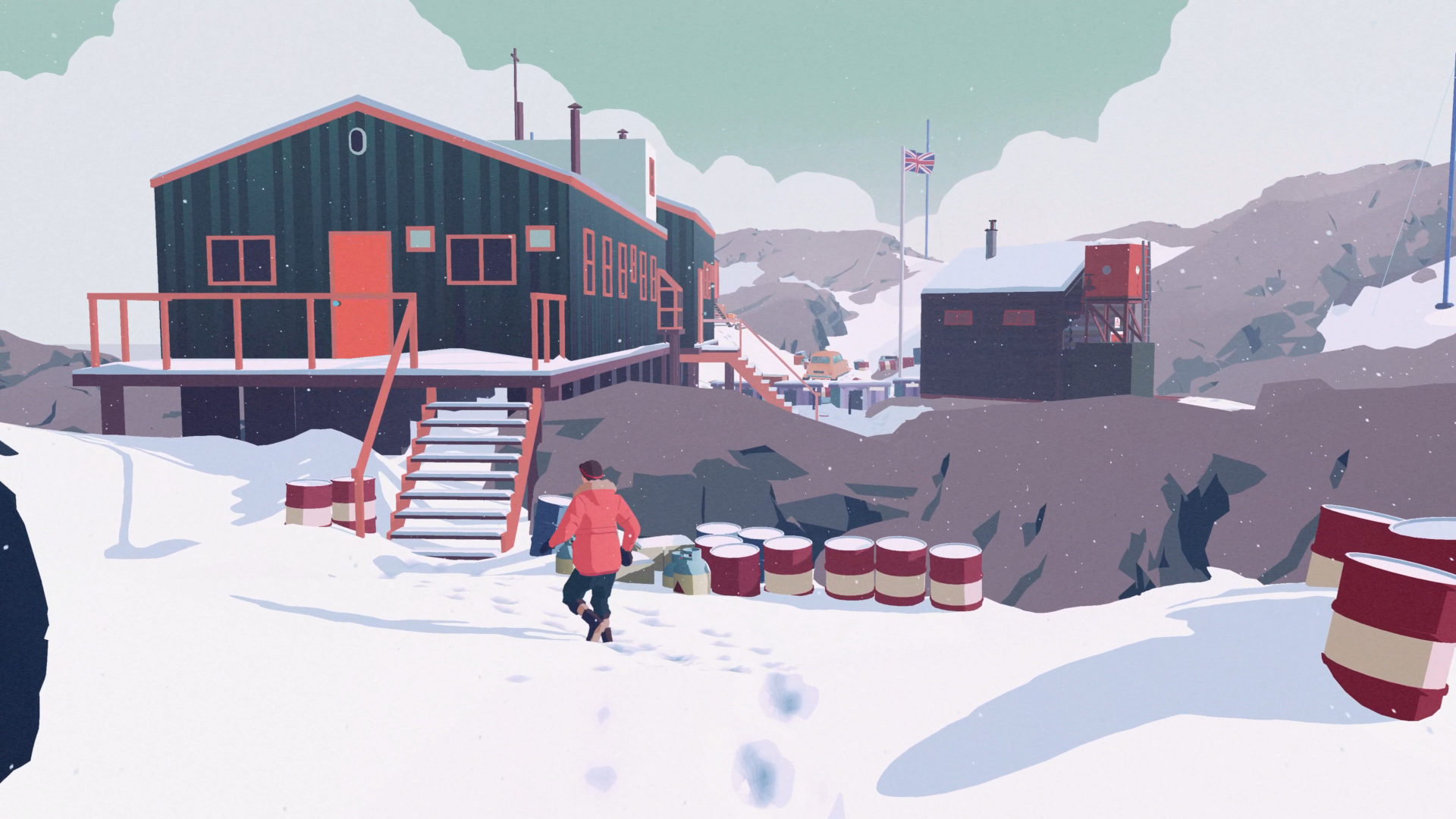 In a snowy mountain landscape, a figure in a red coat approaches a building surrounded by metal barrels. A british flag is in the background.