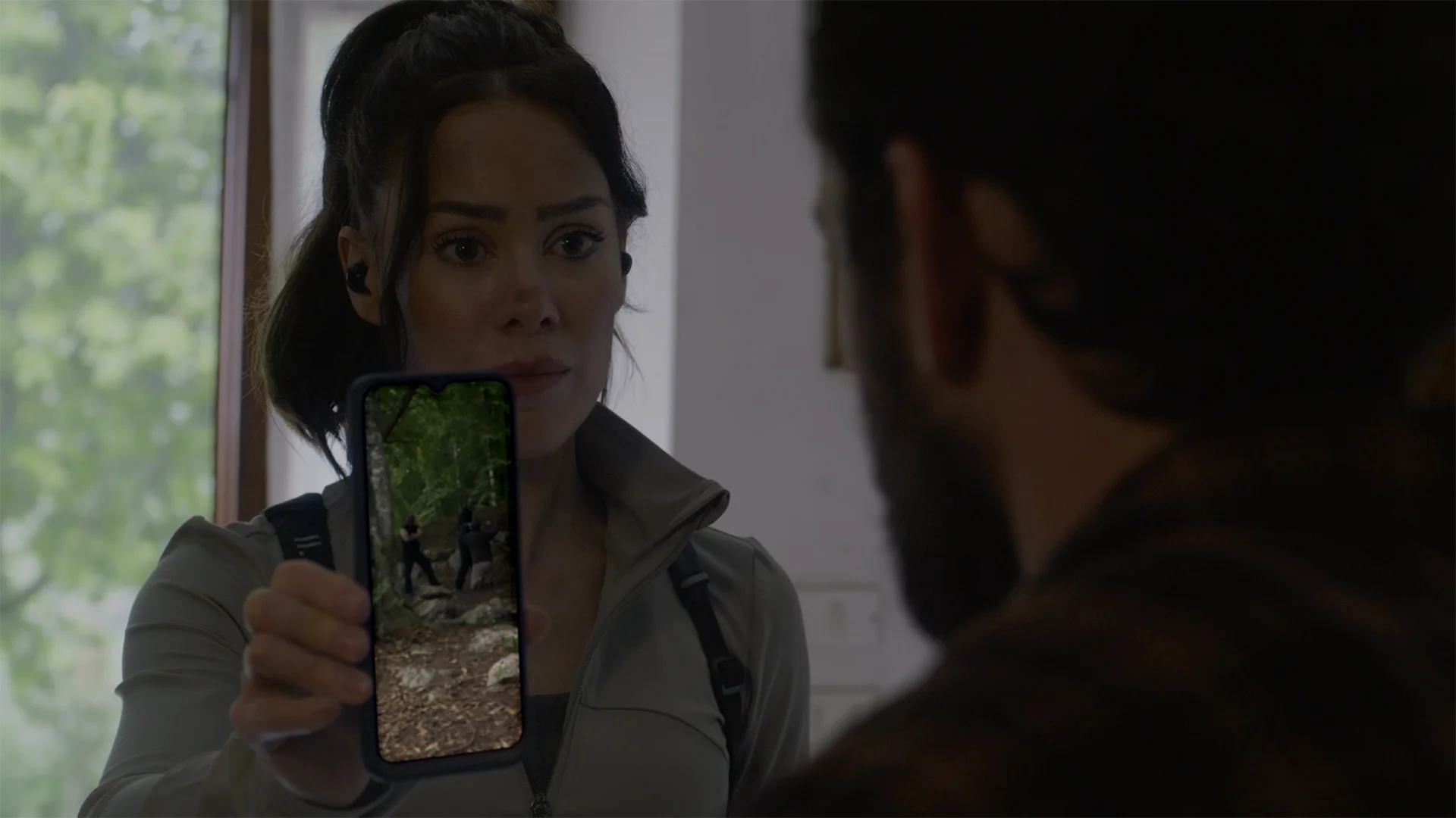 A screenshot of Zanna (Roxanne McKee) in The Run, holding her phone up to Matteo to show him a murder.